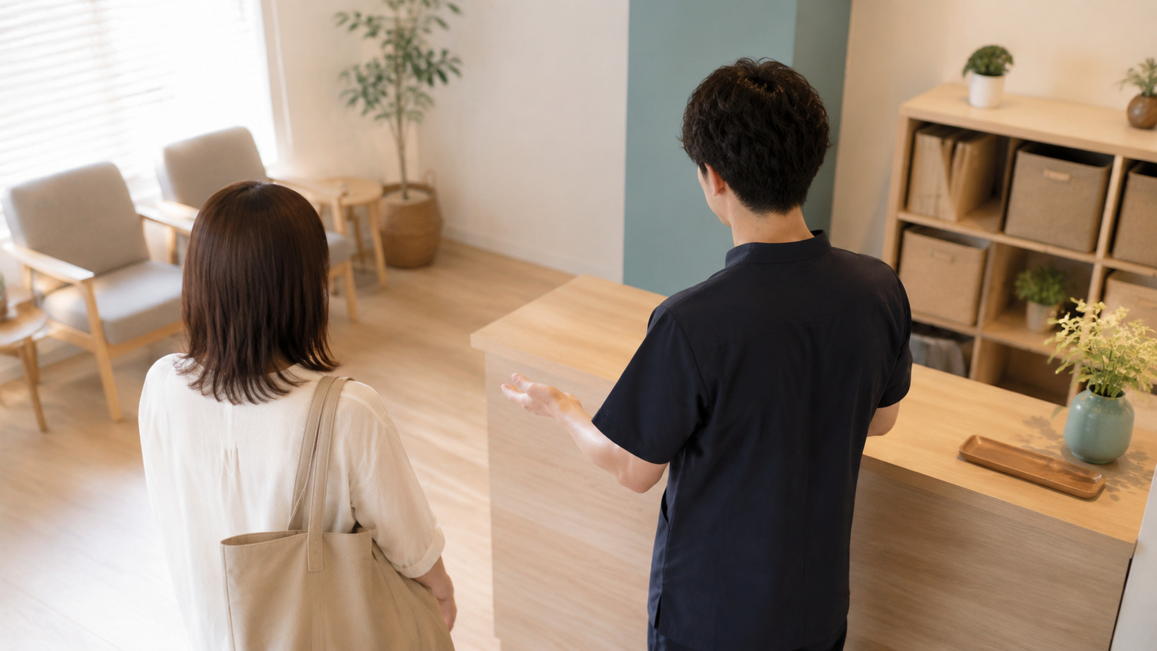 受付カウンター越しに来院者を迎え入れる施術者の後ろ姿